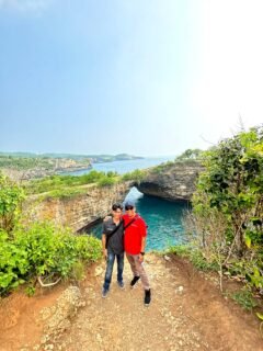 1 day 1 night nusa penida tour package 2 Visitors enjoying the spectacular coastal scenery and natural rock arch at Broken Beach, Pasih Uug, Nusa Penida, Bali, Indonesia.